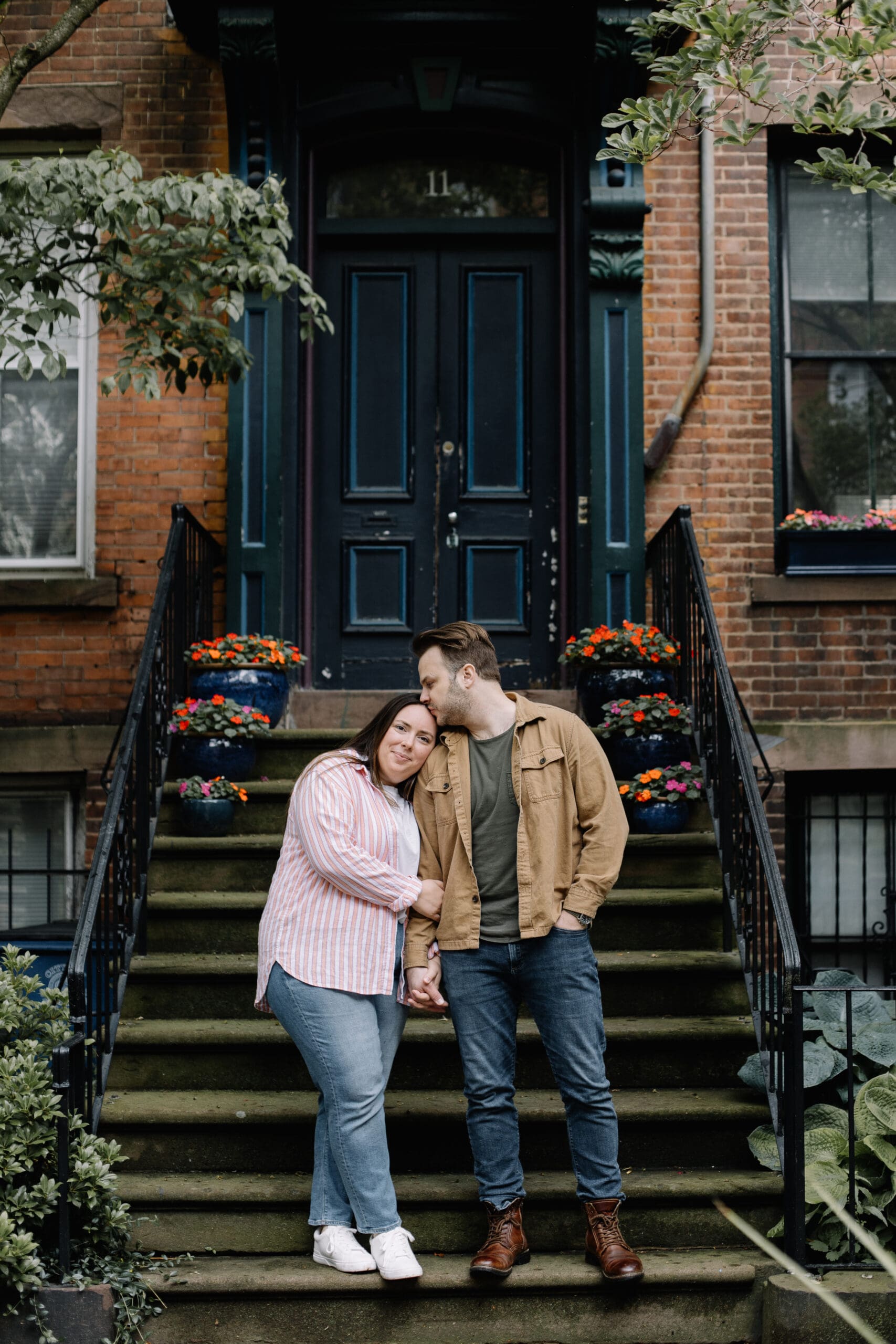 Man and woman standing on stoop while man kisses womans forehead