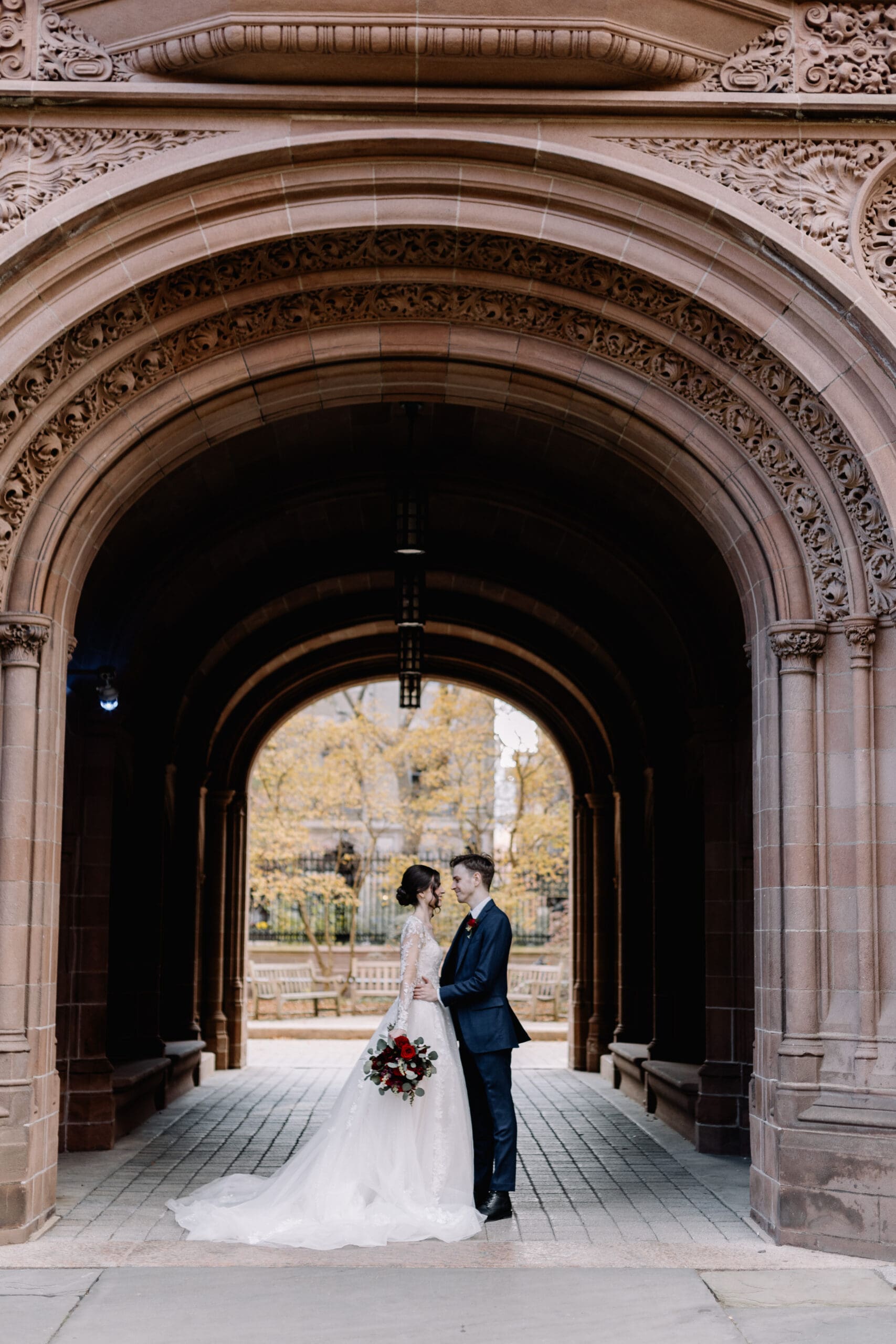 bride and groom standing under archway on yales campus